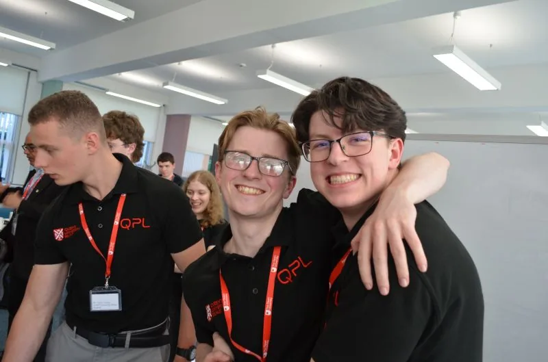 Two QPL team members grinning, arm in arm, at the competition