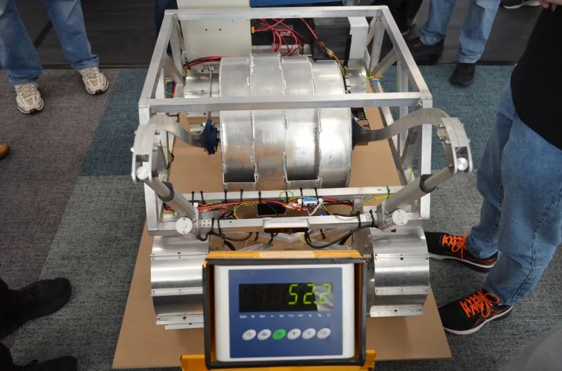 A rover on a weighing scale during inspection, the display reading its mass